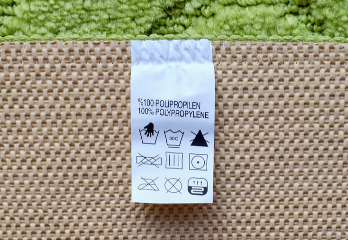 Close up of a carpet label which says the carpet is made of 100 percent polypropylene