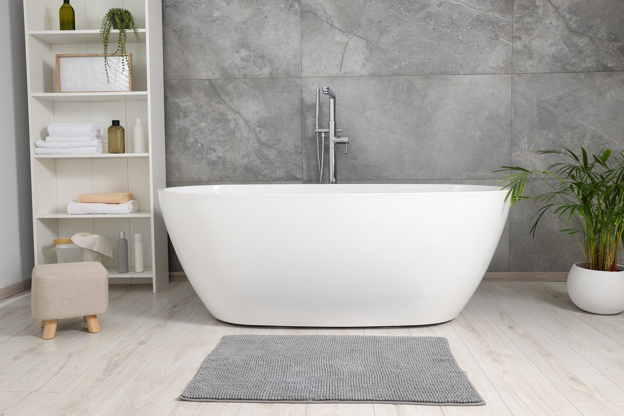 Stylish bathroom interior with ceramic tub and rug